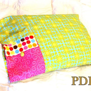 May include: A colorful pillow with a patchwork design. The pillow is made of three different fabrics: a turquoise fabric with a yellow floral pattern, a pink fabric with a white swirl pattern, and a multi-colored fabric with polka dots. The pillow has a yellow button in the center.