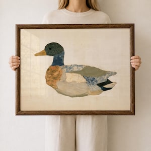 Könnte beinhalten: Ein gerahmtes Wandbild, das die Silhouette einer Stockente aus verschiedenen Stoffstücken zeigt. Die Ente hat einen dunkelgrünen Kopf, einen gelben Schnabel und einen Körper aus gemusterten Textilien in Blau-, Beige- und Grüntönen.