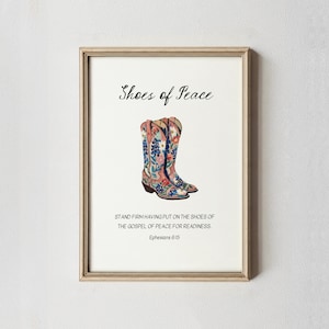 May include: Framed art print featuring a pair of watercolor cowboy boots with floral patterns in pink, blue, and white. The text "Shoes of Peace" is above the boots, with a Bible verse below.