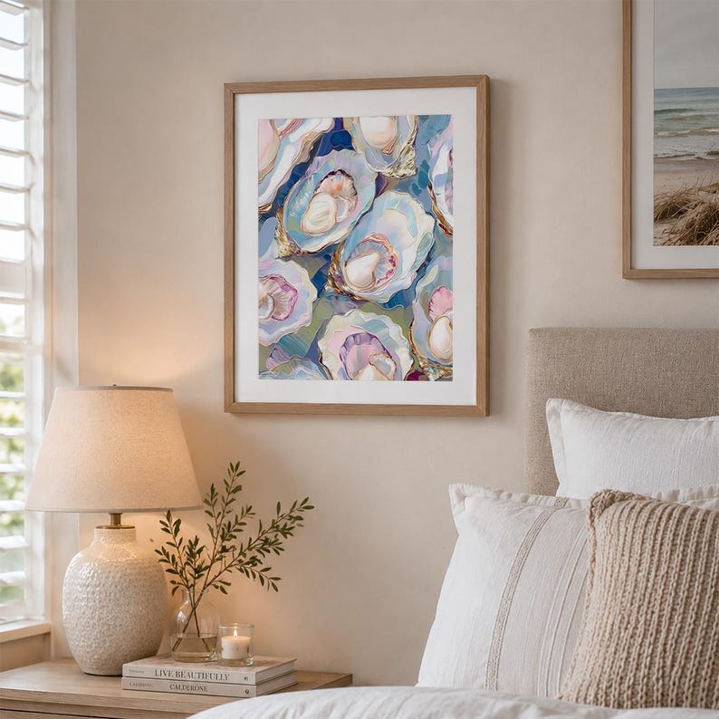 May include: A framed art print featuring an abstract painting of oysters. The artwork showcases a cluster of open oyster shells in shades of blue, pink, and gold, set against a dark blue background. The print is displayed in a light brown wooden frame.