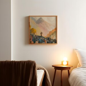 May include: A framed watercolour painting shows a figure speaking to a crowd with mountains in the background. The artwork uses a warm colour palette with orange, pink, and blue tones. The wooden frame provides a natural element to the art piece.