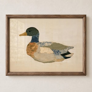 May include: A framed wall art piece featuring a collage of various fabric scraps arranged to form the shape of a mallard duck. The duck is composed of patches in shades of green, blue, tan, and white with floral and striped patterns, enclosed in a dark wood frame.