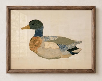 May include: A framed wall art piece featuring a collage of various fabric scraps arranged to form the shape of a mallard duck. The duck is composed of patches in shades of green, blue, tan, and white with floral and striped patterns, enclosed in a dark wood frame.