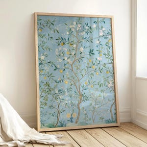 Peut inclure: Une impression d'art encadrée avec un fond bleu clair, présentant un motif botanique. L'œuvre représente un arbre orné de citrons jaunes, de fleurs blanches et de feuilles vertes. Le cadre est en bois clair.