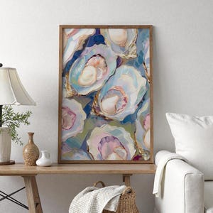 May include: A framed art print featuring an abstract painting of oysters. The artwork showcases open oyster shells in shades of blue, pink, and gold, with a textured, painterly style. The wooden frame adds a rustic touch to the coastal-themed art.