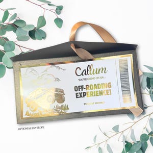May include: A gift voucher for an off-roading experience, presented in a dark grey envelope with a gold ribbon. The voucher features gold foil detailing, including a 4x4 vehicle graphic and the name "Callum". Text reads "OFF-ROADING EXPERIENCE!"