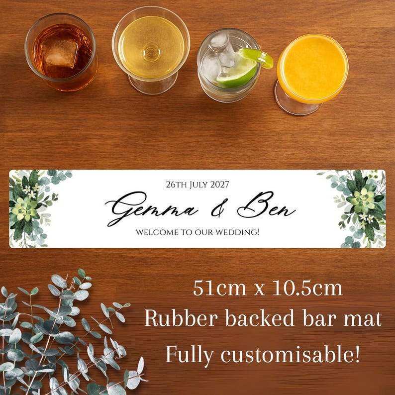 K&ouml;nnte beinhalten: Eine Holzbar mit vier Cocktails und einer rechteckigen Bartmatte. Die Bartmatte ist wei&szlig; mit dem Text "Gemma & Ben" und "WELCOME TO OUR WEDDING!". Die Matte misst 51 cm x 10,5 cm.