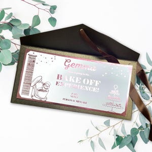 May include: A gold and brown invitation with a pink foil design. The invitation says "Gemma, you're going to the Bake Off Experience!" with a picture of a stand mixer and a tiered cake stand.