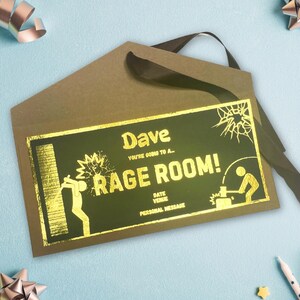 May include: Gold foil invitation with a black background and the text "Dave You're going to a Rage Room!"  The invitation is folded in half and tied with a black ribbon.