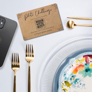 May include: A brown card with the text "Photo Challenge" and a QR code. The text below the QR code reads "Scan to upload to our album. We'd love you to take a picture of: A toast being made."