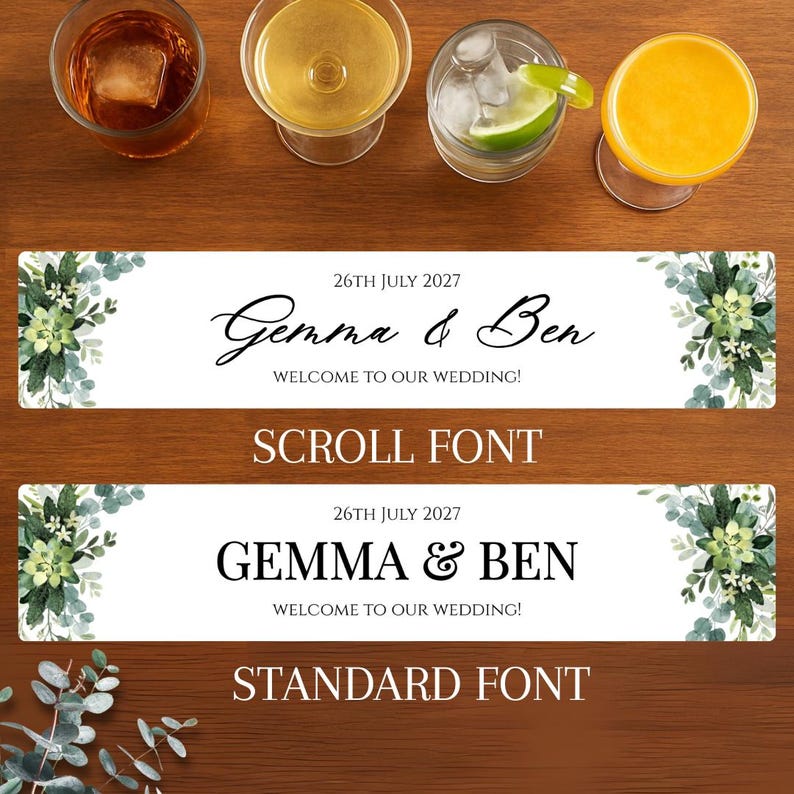 K&ouml;nnte beinhalten: Ein Holztisch zeigt vier Cocktails und zwei Hochzeitsbanner-Designs. Die Banner lesen "Gemma & Ben" und "Willkommen zu unserer Hochzeit!" in Schrift- und Standardschrift. Blumenschmuck und das Datum "26. Juli 2027" sind ebenfalls vorhanden.
