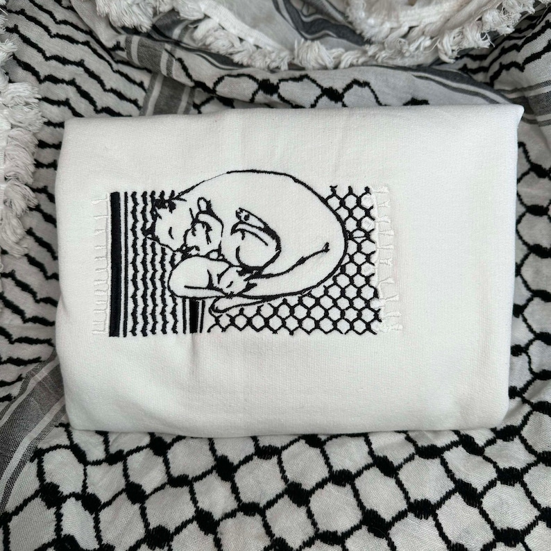 May include: White embroidered tote bag featuring a black and white illustration of two cats cuddling. The illustration is surrounded by a black and white geometric pattern.