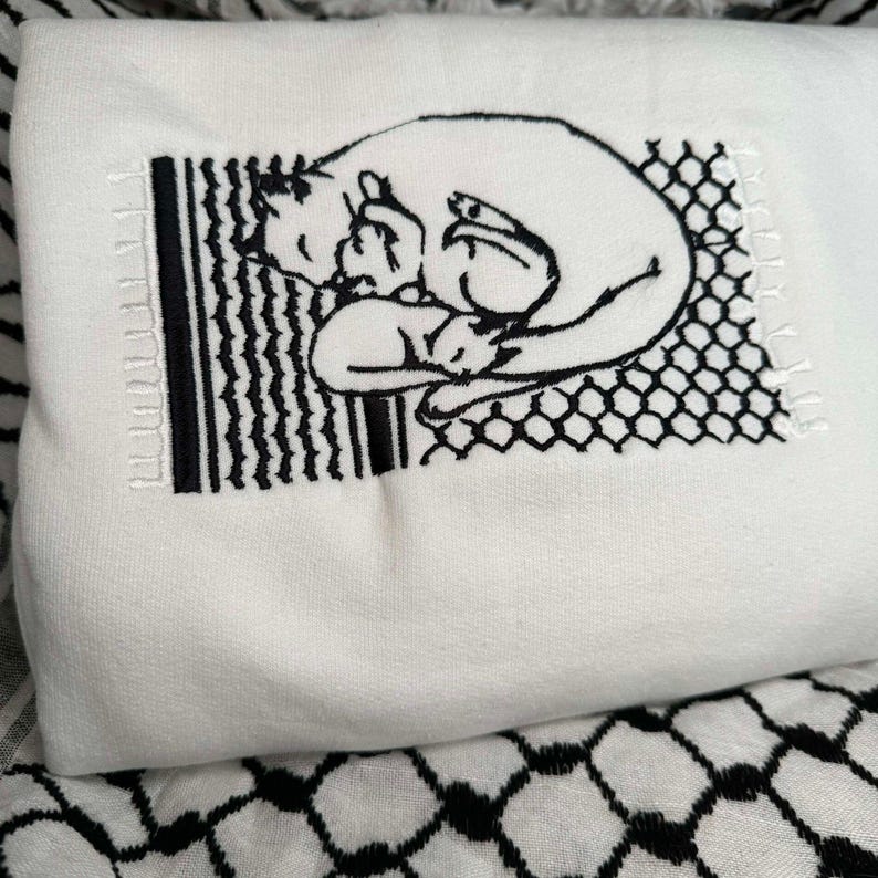 May include: White sweatshirt featuring a black embroidered design of two cats cuddling inside a fence. The design is in a vintage style.