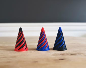 Puede incluir: Tres conos decorativos con un patrón en espiral. Los conos son rojo, azul y negro.