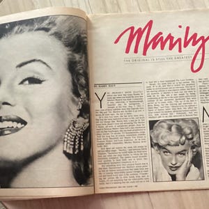 May include: A vintage magazine spread featuring a large black and white portrait of Marilyn Monroe on the left page and the red text Marilyn The Original Is Still The Greatest on the right page, accompanied by columns of printed article text.