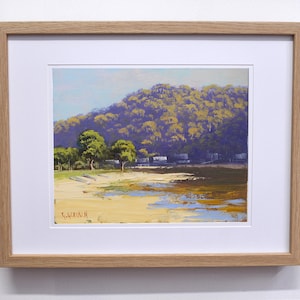 May include: A framed painting of a landscape with a hill covered in trees in the background and a sandy beach in the foreground. The sky is blue and the water is a light blue. The painting is signed "G.J. Weir 1998" in the bottom left corner.