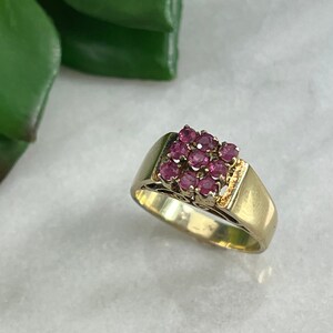 Può includere: Un anello d'oro con un gruppo quadrato di pietre di rubino rosa incastonate in un design a filigrana.