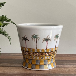May include: White ceramic planter with a yellow, red, and green geometric pattern and palm tree illustrations.