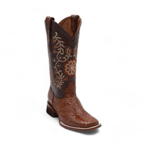 May include: A tall brown leather cowboy boot featuring a dark brown shaft with intricate cream and orange floral embroidery. The lower foot section displays a detailed embossed floral pattern, a square toe, and a low stacked block heel.