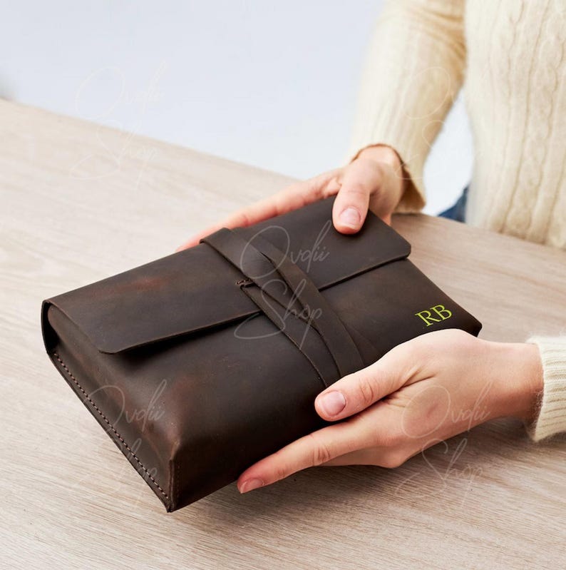 May include: A brown leather journal with a strap closure and the initials "RB" embossed in gold.