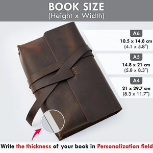 May include: A brown leather book cover with a strap closure. The cover is designed to fit a book with dimensions of 10.5 inches by 14.8 inches, 14.8 inches by 21 inches, or 21 inches by 29.7 inches. The text "Write the thickness of your book in Personalization field" is visible at the bottom of the image.