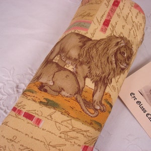 Peut inclure: Un étui à lunettes en tissu beige avec un motif de lion et de lionceau. L'étui est orné d'un motif rayé rouge et blanc et le texte "The Glass Case" est imprimé sur une étiquette séparée.