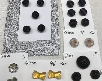 May include: Assortment of vintage glass buttons in various shapes and sizes. Includes black, gold, and clear buttons, some with decorative patterns. Sizes range from 7/16 inch to 3/4 inch.