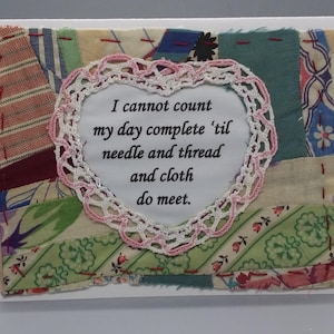 May include: A white card with a pink and white heart-shaped lace doily. The doily has a quote inside that reads "I cannot count my day complete 'til needle and thread and cloth do meet."