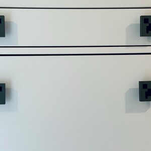 May include: White dresser with four black and green Minecraft Creeper face drawer pulls.