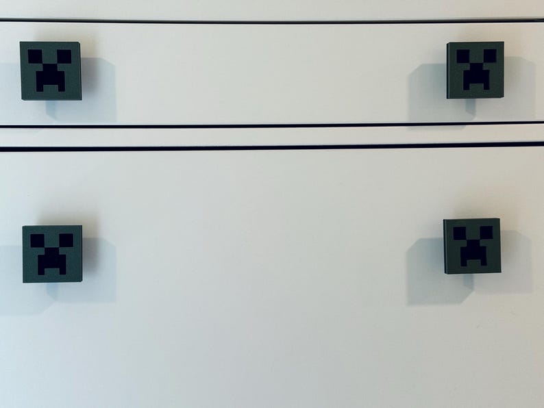 May include: White dresser with four black and green Minecraft Creeper face drawer pulls.