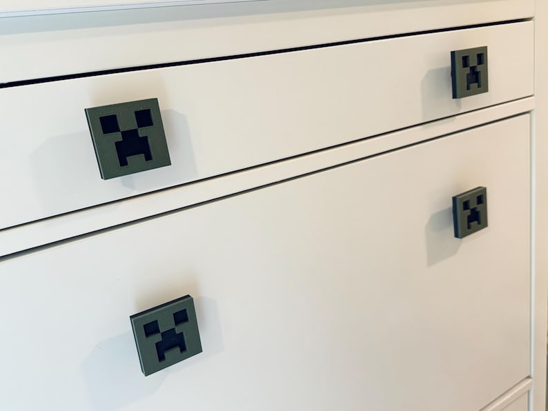 May include: White dresser with four drawers. Each drawer has a green Minecraft Creeper face pull handle.