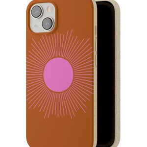 May include: A brown phone case with a pink sun design. The case is made of a sustainable material and has a raised edge to protect the screen.