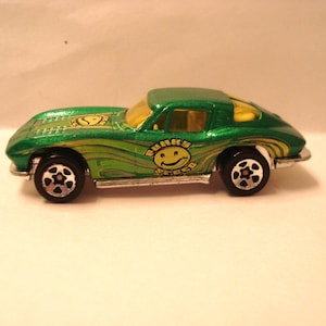 May include: A green toy car with a yellow smiley face logo that says "Funky Speed". The car has a green body with yellow wave designs and black wheels. The windows are yellow.