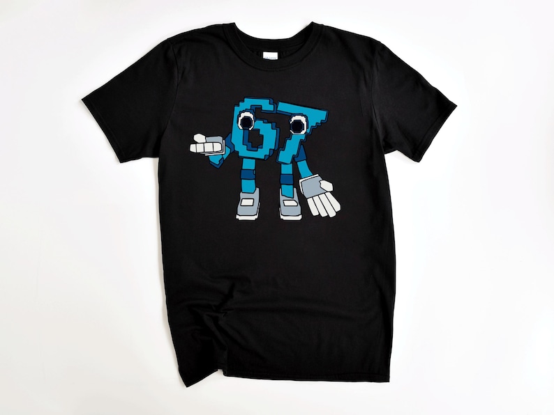 May include: Black t-shirt featuring a pixelated cartoon character in shades of blue, gray, and white. The character is a stylized representation of the numbers "67" with arms, legs, and gloves. The design is centered on the shirt.
