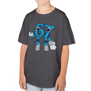 May include: Dark gray t-shirt featuring a pixelated cartoon character of the number 67 in blue. The character has arms, legs, and a friendly expression. The shirt is made of a soft material.