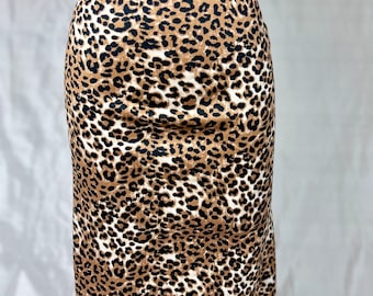 May include: A brown and white leopard print skirt. The skirt is knee-length and has a fitted silhouette.