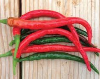 May include: A group of red and green chili peppers, some are curved and some are straight, on a wooden surface.