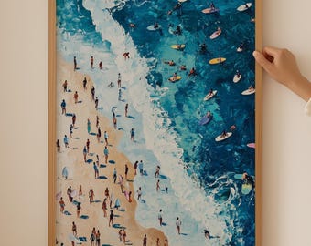 以下が含まれることがあります： 砂浜に人々、水の中にサーファーがいるビーチのシーンを描いた額縁付きの絵画。絵画は明るい木製の額縁に入っていて、背景は白です。