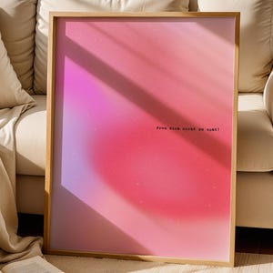 Könnte beinhalten: Ein rechteckiges Wandbild in einem hellen Holzrahmen mit einem leuchtenden Farbverlauf in Pink und Rot, der einen weichen, nebligen Aura-Effekt erzeugt. Der Text "Freu dich nicht zu spät!" ist in kleiner, schwarzer Schreibmaschinenschrift zu sehen.