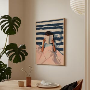a cozy indoor setting with a framed painting of a person reading a book, a table with a vase of flowers, and a potted plant.