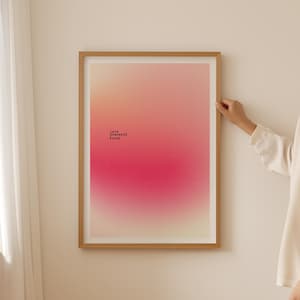 Könnte beinhalten: Ein gerahmter Kunstdruck mit einem Farbverlauf von Pfirsich bis tiefem Rosa. Die Worte "love yourself first" sind unten links in Schwarz gedruckt. Der Rahmen hat eine hellbraune Farbe.