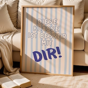 Könnte beinhalten: Ein rechteckiges gerahmtes Wandbild mit vertikalen hellblauen Streifen auf beigem Hintergrund. Der Text DIESE KLASSE IST BESSER MIT DIR! ist in Dunkelblau gedruckt, wobei das Wort DIR! in einer größeren, fetten Handschrift-Schriftart erscheint.