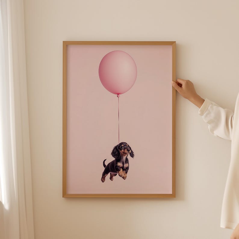 a woman holding a poster of pink balloon above a Dachshund