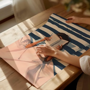 A person's hands are holding a book with an illustration of a person reading on a blue and white striped background.
