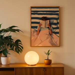 a wooden cabinet with a lamp on top, a potted plant, and a framed painting of a woman reading a book.