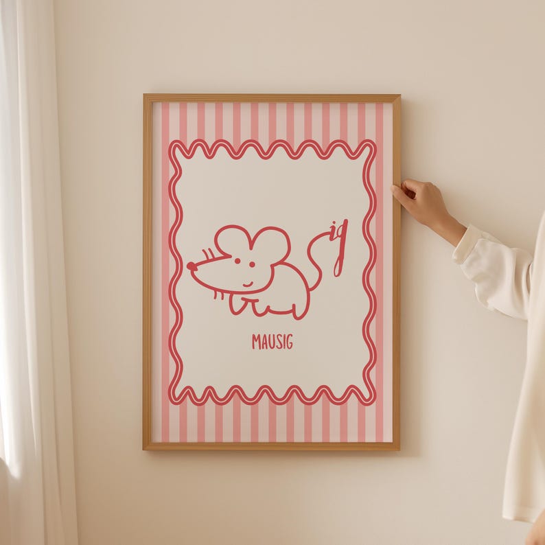 May include: A framed print with a cartoon mouse illustration in red. The mouse is drawn with simple lines and the word "MAUSIG" is below it. The background has pink and white vertical stripes, and the frame is a light brown colour.