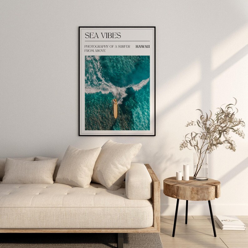 May include: A framed print with the text "SEA VIBES" and "PHOTOGRAPHY OF A SURFER FROM ABOVE" in black text. The image shows a surfer on a surfboard in the ocean, photographed from above. The text "HAWAII" is in the top right corner.