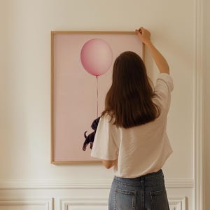 a woman is holding a balloon in front of a painting