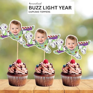 May include: Three cupcakes with Buzz Lightyear-themed toppers featuring a baby's face. The cupcakes have chocolate frosting, pink swirls, and are decorated with berries and chocolate drizzle. The toppers read "Personalized Buzz Lightyear Cupcake Toppers."