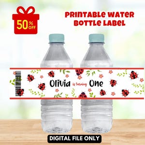 May include: Two clear plastic water bottles with light blue lids. A red and white label wraps around the bottles, featuring ladybirds, flowers, and the text "Olivia is turning One." A red gift box with "50% OFF" is in the upper left.